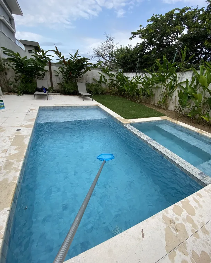 Piscina sendo limpa com peneira